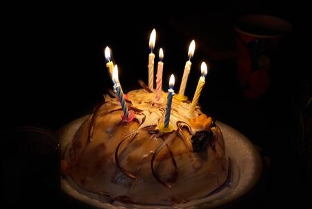 Birthday cake with candles on dark background. Cake for special celebration. This cake is perfect to a birthday party or any other celebration with an interesting flame lightの写真素材