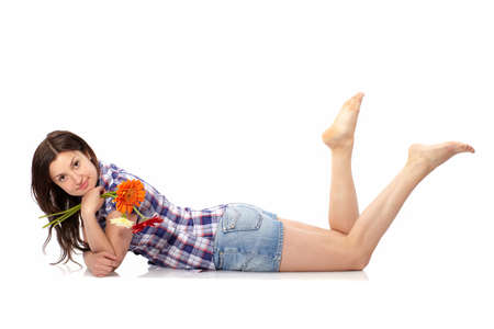 Beautiful young woman lying down on the floor with flowers isolated on white. Casual young relaxed and happy woman cut out in full length body.の写真素材