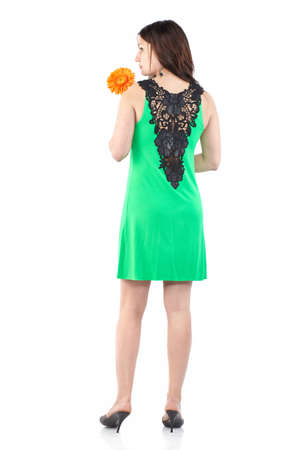 Back view portrait of a young beautiful woman in green summer dress. Woman with gerbera flowerの写真素材