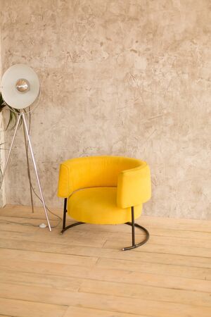 The interior of the room with a yellow chair, retro lamp on the wall with decorative plaster, wooden floorの写真素材