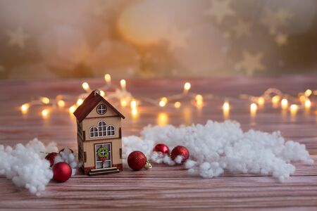 Beautiful toy wooden houses on a snowy background, Christmas toys, on a wooden background with garlandsの写真素材