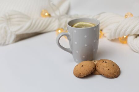 Backgrounds and textures. Lemon tea, cookies and tangerines on a white background with a knitted scarf with flower garlandsの写真素材