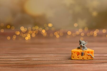 A toy mouse sits in cheese on a wooden starry background, a symbol of 2020.の写真素材