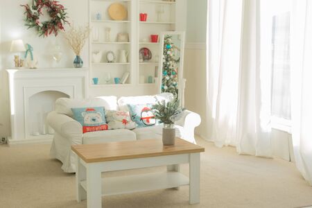 The interior of the Christmas room with a large window, a white sofa with pillows at the coffee tableの写真素材