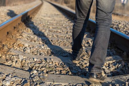 A man walks along the railway, crossing the sleepers. Reckless behavior.の写真素材