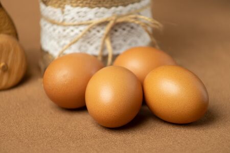 Fresh natural chicken eggs on a wooden stick. Farm brown eggs. On a background of brown fabricの写真素材