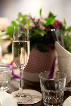 a glass of wine with bubbles on the background of flowers at the banquet table in a restaurantの写真素材