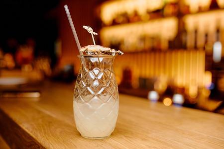A beautiful photo of a pineapple cocktail on the bar counter in soft light