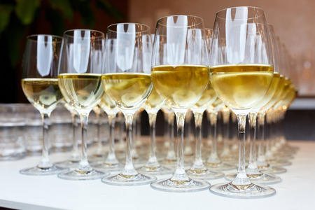 Close-up photo of wine glasses with white wine on the tableの写真素材