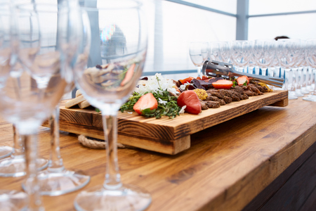 grilled steak with strawberries and french mustard on a wooden board and empty glasses for wine in the restaurantの写真素材