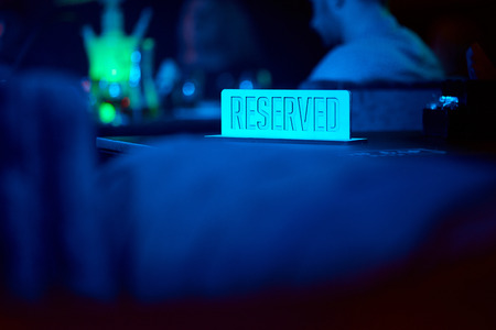 metal plate reserved in neon light on a table in a restaurantの写真素材