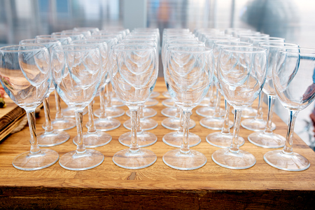 A lot of empty wine glasses on a wooden table in a restaurantの写真素材