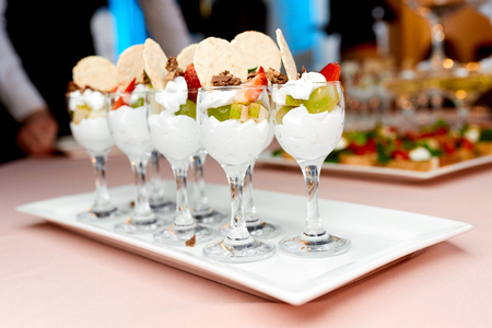 glass cups with fruit snacks and cream on the table in the restaurantの写真素材