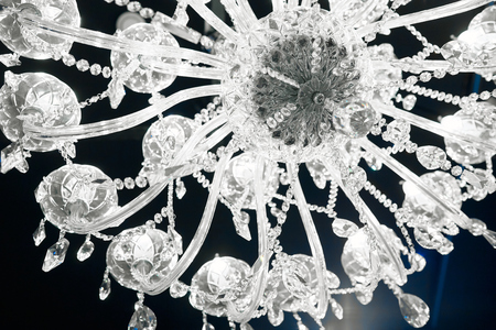 transparent glass chandelier with transparent beadson the ceiling in the darkの写真素材
