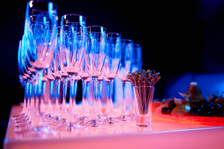 empty champagne glasses in neon light, next to toothpicks on a table in a restaurantの写真素材