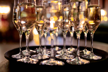glasses with white wine on a tray on the table in the restaurantの写真素材