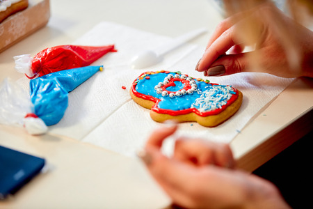 the woman decorates gingerbread in the form of mittens on a napkin on the tableの写真素材