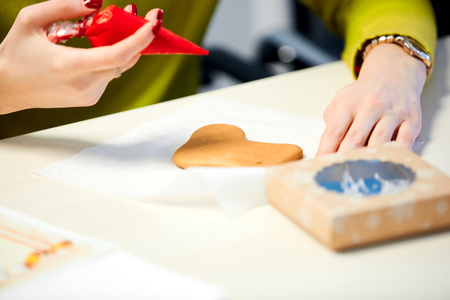 the woman decorates gingerbread in the form of mittens on a napkin on the tableの写真素材