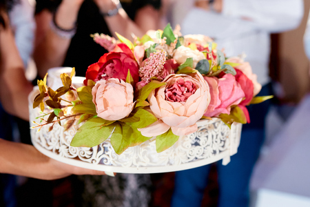 beautiful bouquet of flowers in a handmade box on women's hands outdoors at a weddingの写真素材