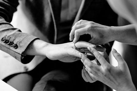female hands dress a wedding ring on a man's handの写真素材