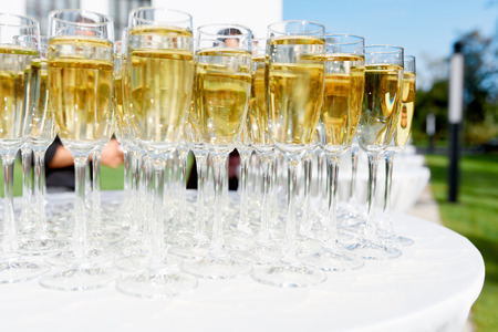 glasses of champagne stand on a white tablecloth on a table in the fresh air at a weddingの写真素材