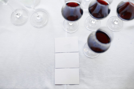 White empty business cards for your logotype or text on a white tablecloth with wine glassesの写真素材