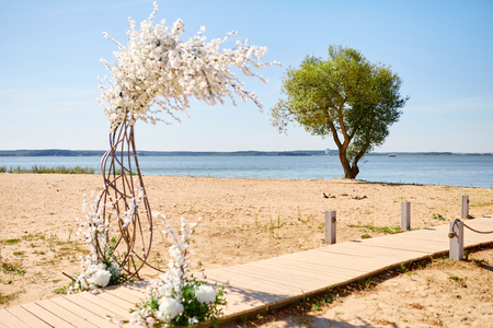 beautifully decorated outdoors ceremony area with sea and tree at the backgroundの写真素材