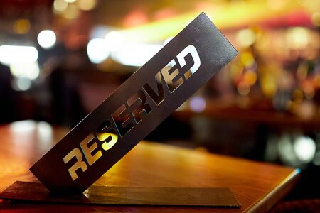 A black, metal, square, clear, reservation plate is on the table in a cafe-restaurant and reserves a place for certain guests of the restaurant against the background of the barの写真素材