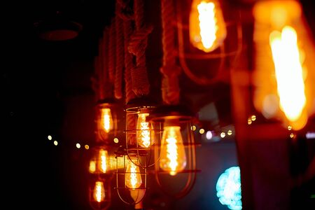 Cozy, lamp lighting in an institution on a wooden wall. Glass bulbs hanging on the ceiling shine...