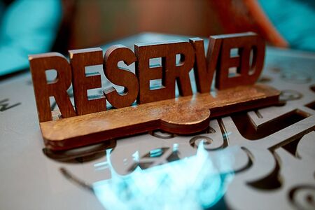 A wooden brown plate in a cafe-restaurant, which stands on a glass table and reserves a place for certain guests of the institutionの写真素材