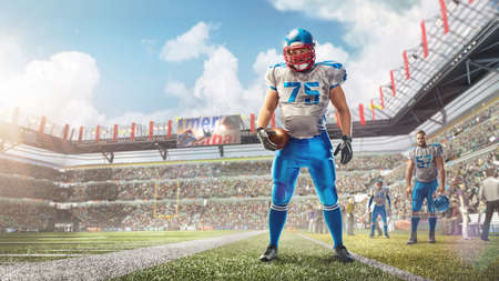 sport. An American football player stands in the stadium and holds a ball in his hand. Daytime stadium full of fans. Manの写真素材