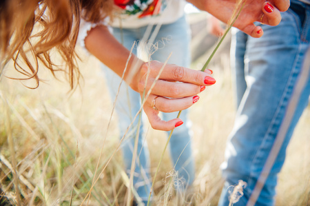 girl touching hands in the national costume of grass spikelets at sunsetの写真素材