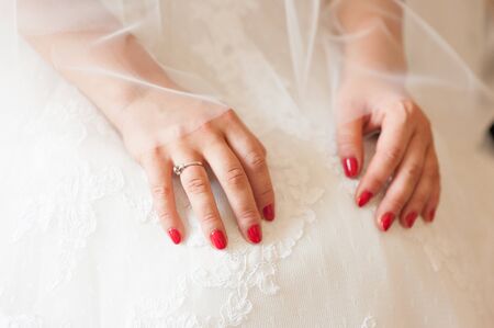 Tender beautiful bride's hands on elegant white wedding dress closeup luxuryの写真素材
