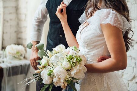 wedding bouquet with peonies in the hands of the bride in white dressの写真素材