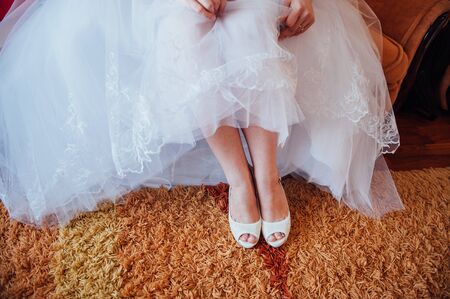beautiful bride's feet in white shoes and white dressの写真素材