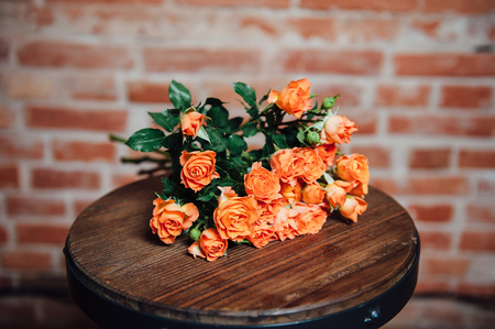 Mini roses on vintage wooden surface near brick wallの写真素材