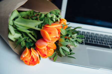 Laptop on white floor with flowers. tulipsの写真素材