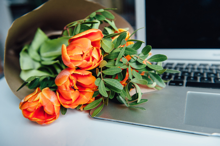 Laptop on white floor with flowers. tulipsの写真素材