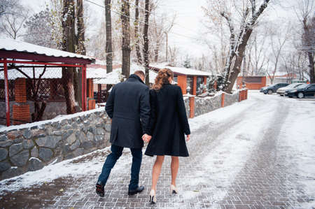 bride and groom is running with joined hands on a winter park roadの写真素材