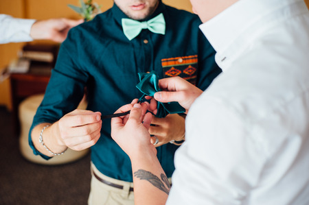 groom wears stylish bow tie using friend.の写真素材
