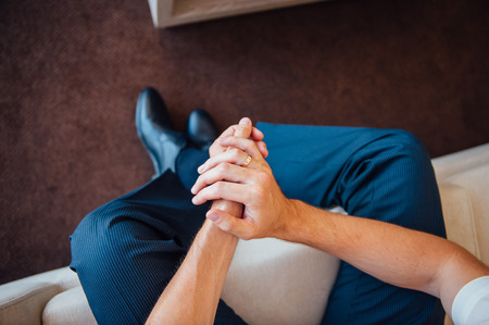 a man sits with hands clasped . View from aboveの写真素材