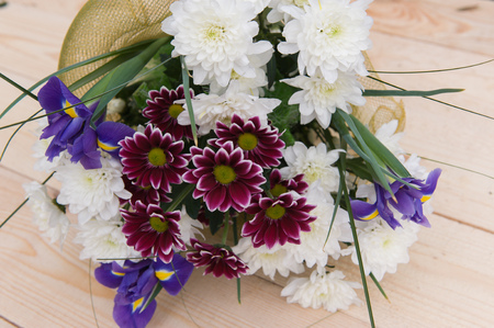 beautiful spring bouquet of flowers with chrysanthemums on a wooden plateの写真素材
