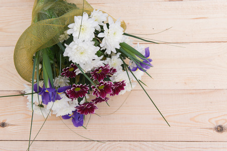 beautiful spring bouquet of flowers with chrysanthemums on a wooden plateの写真素材