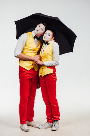 studio shot of two mimes isolated on a white background. with umbrellaの写真素材