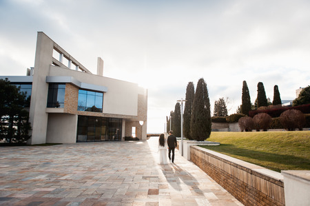 bride and groom is running with joined hands on a city park roadの写真素材