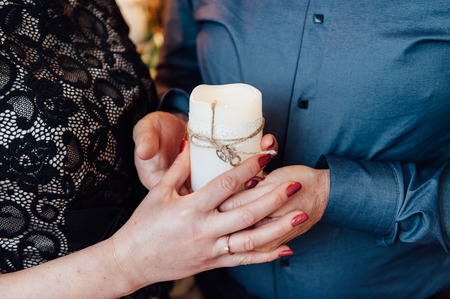 adult couple holding hands with a candle.