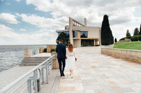 bride and groom is running with joined hands on a city park road sunshineの写真素材