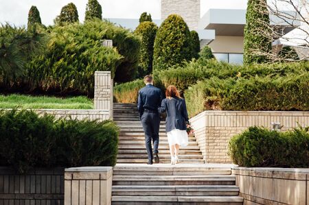 bride and groom is running with joined hands on a city park road sunshineの写真素材