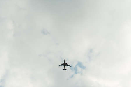 An airplane flying in the blue sky with cloudsの写真素材