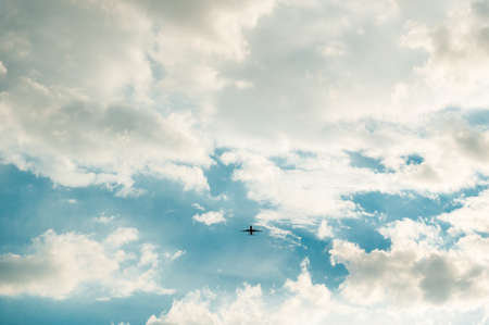 An airplane flying in the blue sky with cloudsの写真素材